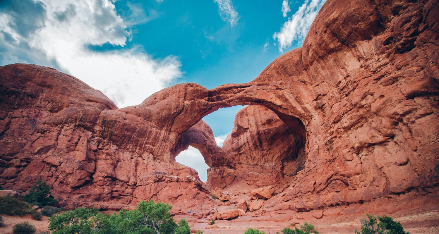 a large rock formation with a couple of people standing in front of it